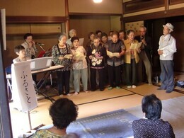 写真：地域の人が集まり、みなさまで懐かしい歌を歌っている様子（地域交流）